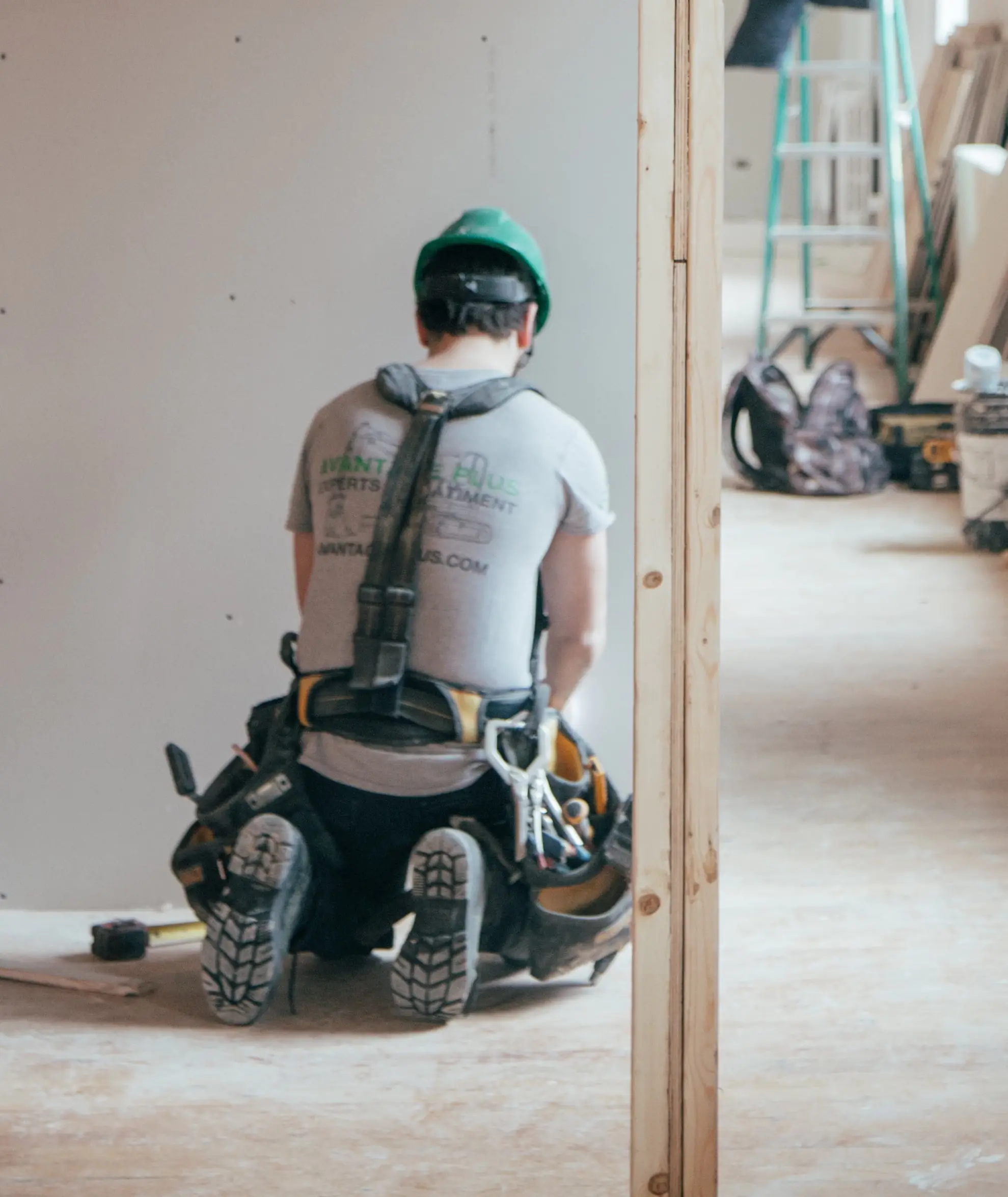 Man with tool belt working on a wall